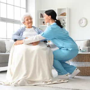 Patient care service at home in Dhaka — nurse and caregiver attending an elderly patient in a hospital bed